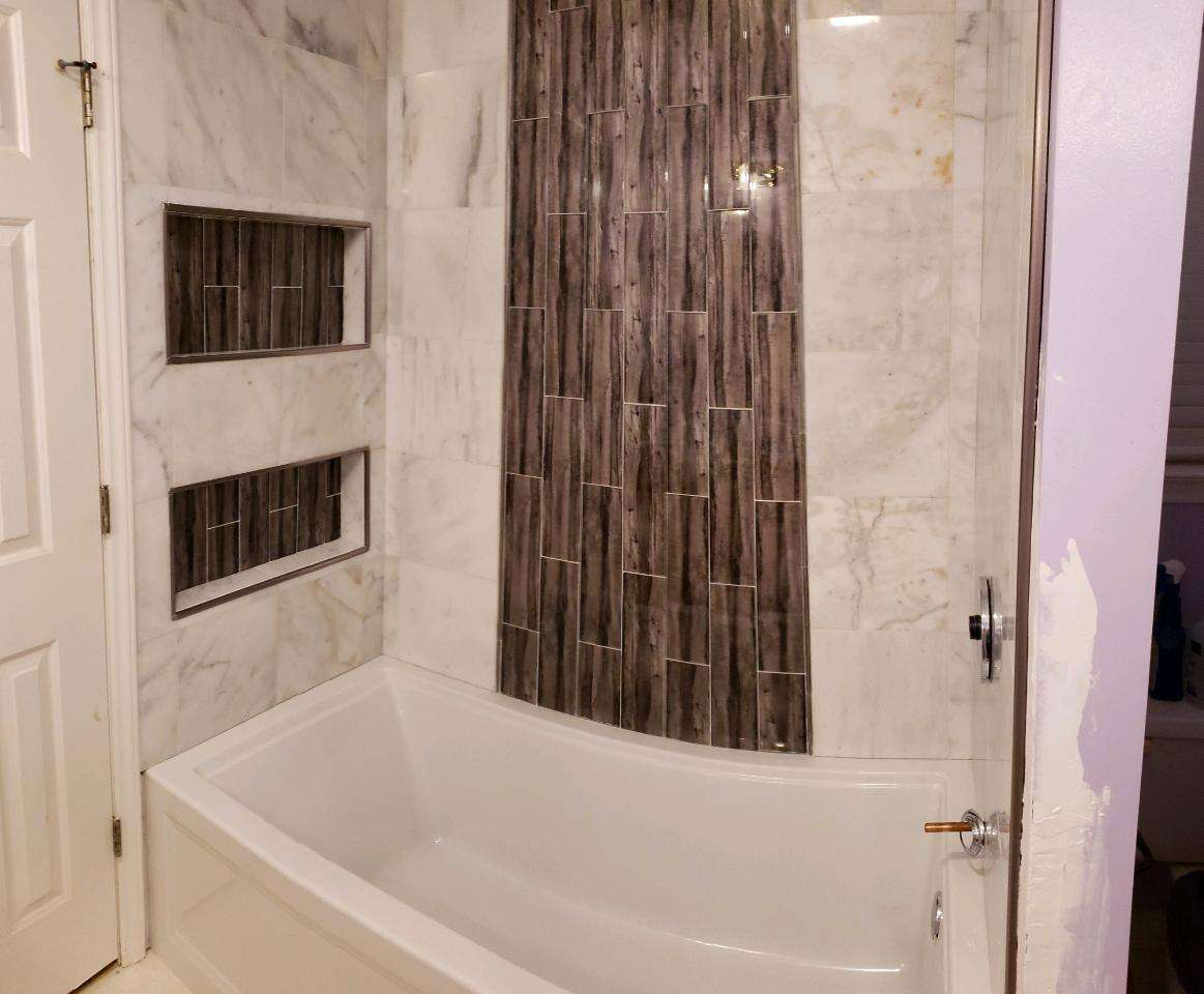 Bath surround with a vertical feature-tile strip and two recessed niches