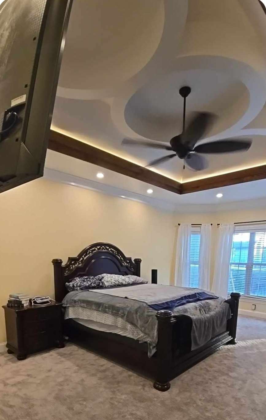 Primary bedroom with a curved tray ceiling, wood trim and cove lighting