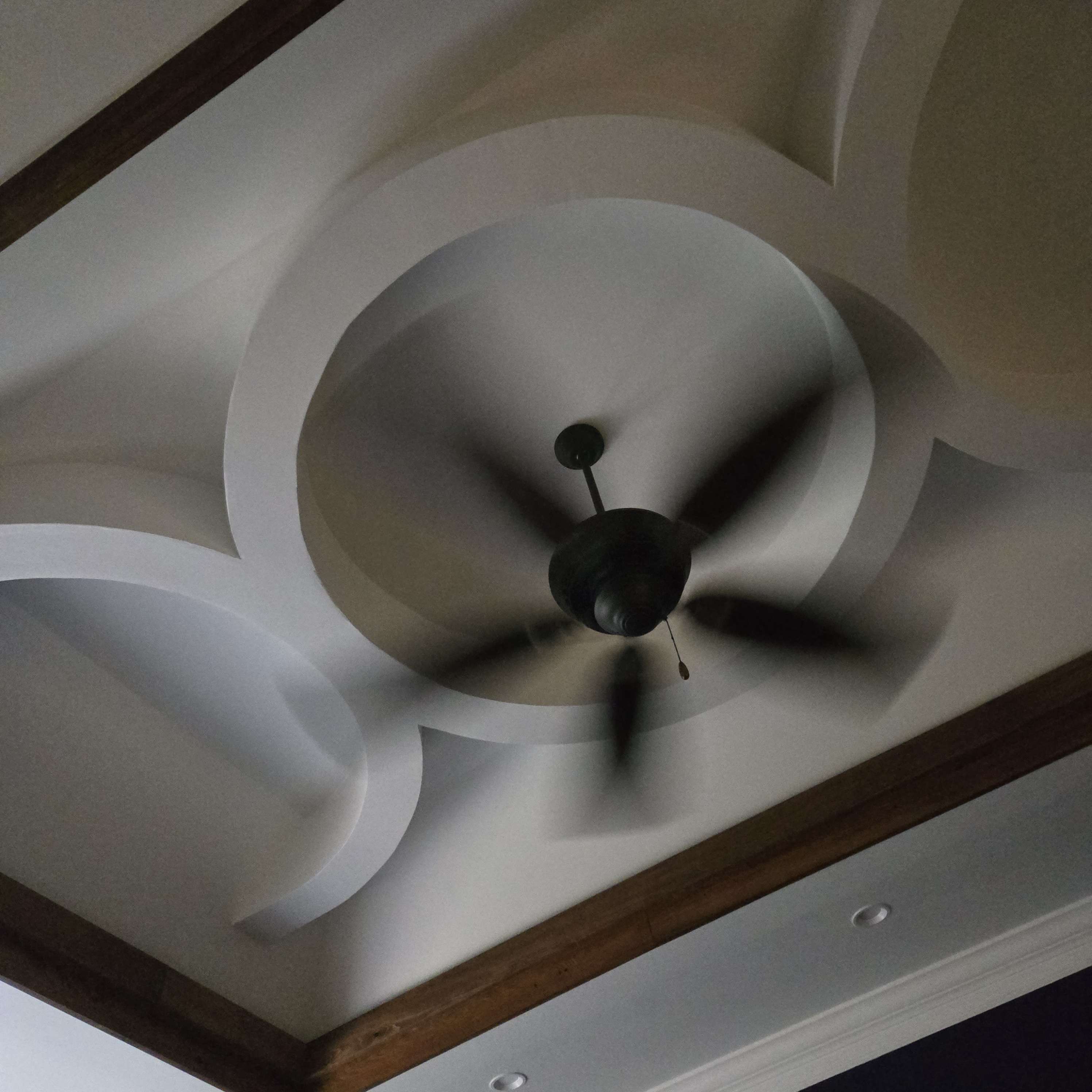 Close-up of the curved drywall tray ceiling and stained wood trim